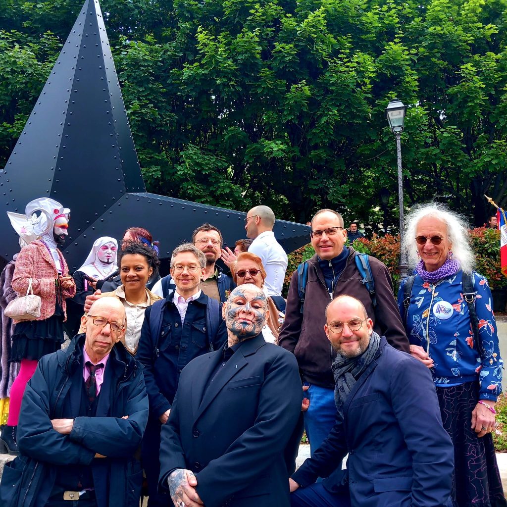 L'artiste au milieu, avec ces tatouage sur le visage, entouré d'une dizaine de membres associatifs