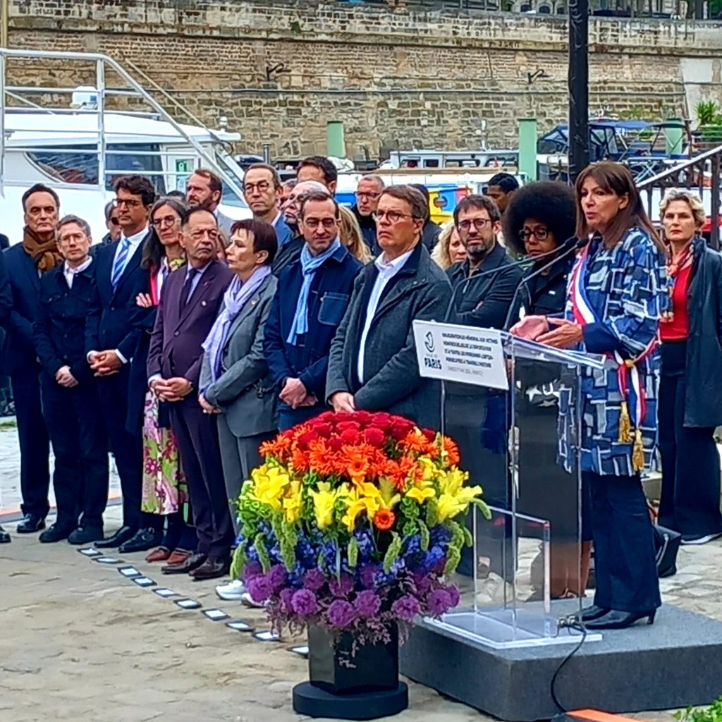 groupe d'une douzaine de personne débout, des élu-e-s ou représentan-e-s officiels écoutant Anne Hidalgo faire un discours