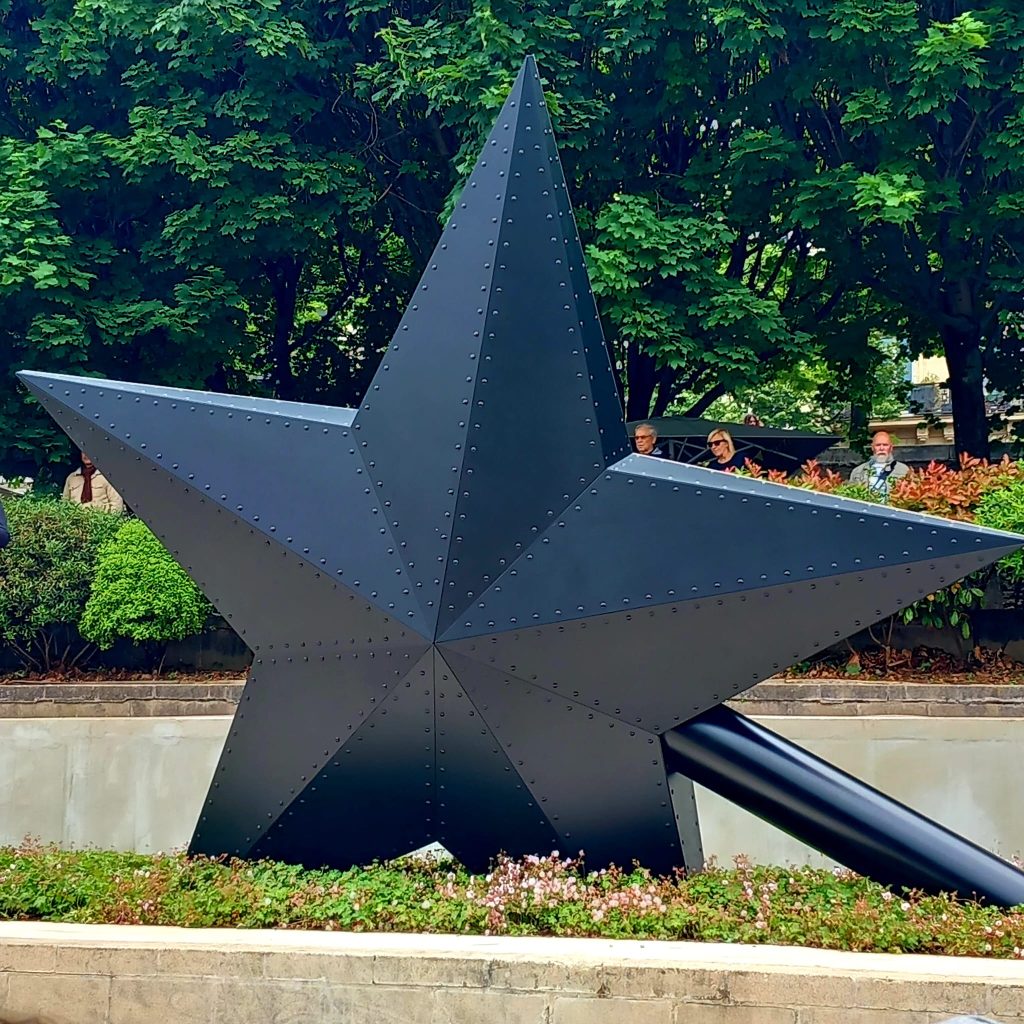 face sombre du monument. Grande étoile (plus de 4m) noire à 5 branches et manche de la baguette rentrant vers le sol